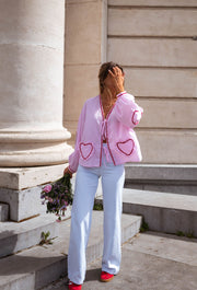 Jean évasé taille haute porté par une femme, vue de trois-quarts, blazer rose, bouquet