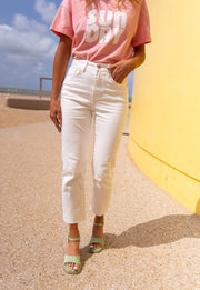 Jean taille haute effiloché blanc porté par une femme, vue rapprochée, t-shirt rose, jean