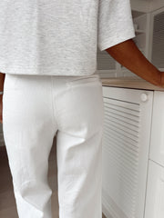 Jean brodé à coupe droite porté par une femme, vue de dos, t-shirt gris, jean blanc