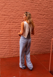 Jean fluide à poches porté par une femme, vue de dos, mur en brique, haut beige