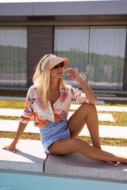 Chemise imprimée à manches longues portée par une femme, assise, bord de piscine, short en jean