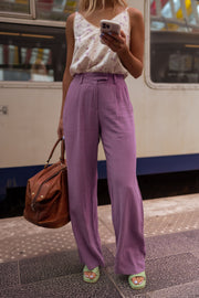 Pantalon en lin fluide porté par une femme, silhouette entière, train, sac marron