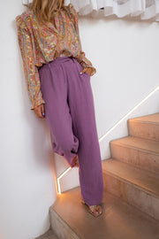 Pantalon en lin fluide porté par une femme, vue de profil, escalier, mur blanc
