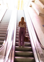 Pantalon en lin fluide porté par une femme, vue de dos, escalator, haut fleuri