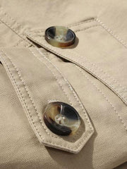 Détail d'une patte en tissu beige et de deux boutons du manteau