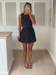 Jupe courte à pois portée par une femme, silhouette entière, placards blancs, sandales