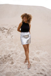 Jupe taille haute à paillettes portée par une femme, silhouette entière, dune, sandales