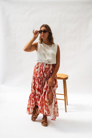 Jupe longue à motifs fendue portée par une femme, silhouette entière, lunettes, haut blanc