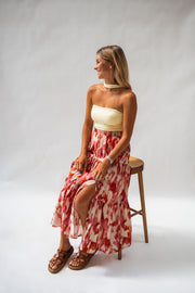 Jupe longue à motifs fendue portée par une femme, vue de trois-quarts, tabouret, haut jaune