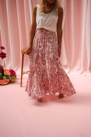 Jupe longue fluide à motifs portée par une femme, en marchant, rideaux roses, jupe longue