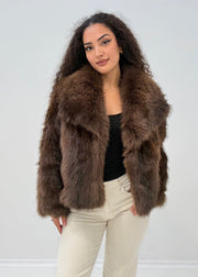 Veste fourrure brun foncé — vue portée en pied, sur un haut noir et pantalon beige large
