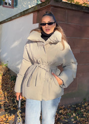 Veste d’hiver courte taupe — vue portée en extérieur, plan moyen sur la ceinture et le matelassage
