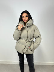 Veste d’hiver courte taupe — vue portée de face en intérieur, pantalon et bottes noirs