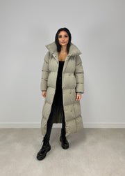 Veste longue taupe à ceinture — vue portée en pied, ouverte sur une tenue noire