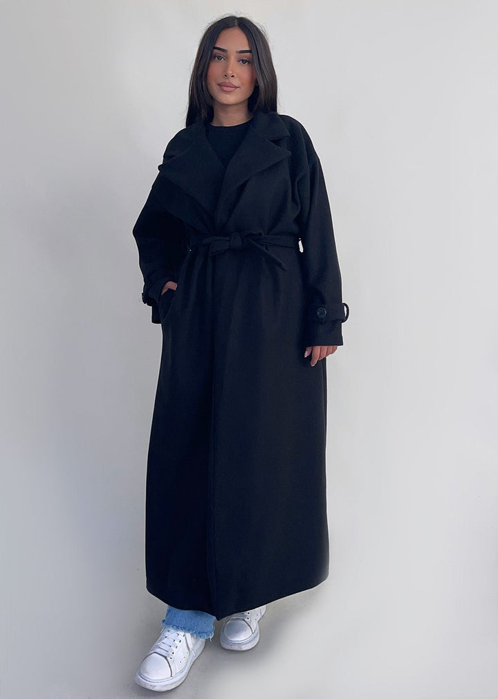 Manteau long noir à ceinture — vue portée de face.