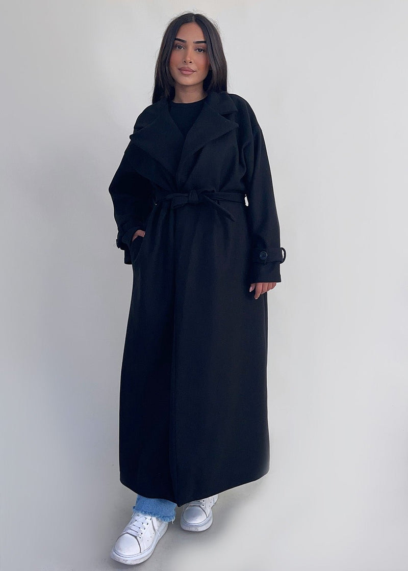 Manteau long noir à ceinture — vue portée de face.