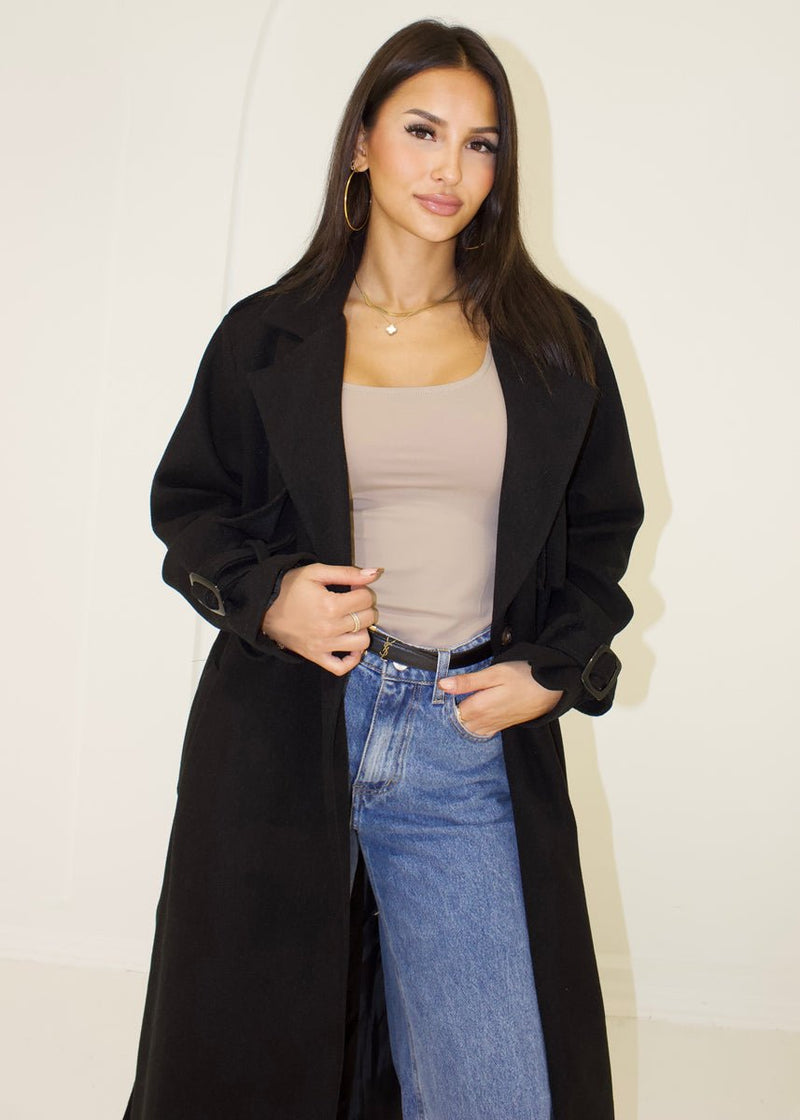 Trench long noir à ceinture — vue portée de face, cadrée à la taille, ouvert