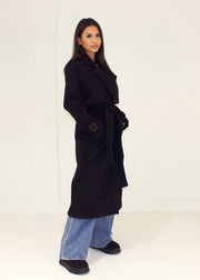 Trench long noir à ceinture — vue portée de profil, ceinturé