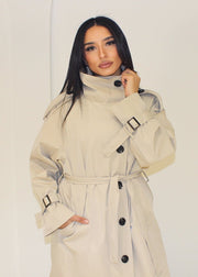 Trench long beige — gros plan du col montant et des boutons noirs