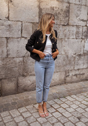 Veste droite à épaulettes portée par une femme, silhouette entière, jean clair, pieds nus