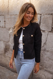 Veste droite à épaulettes portée par une femme, vue de trois-quarts, sourire, haut blanc