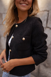 Veste droite à épaulettes portée par une femme, vue rapprochée, boutons dorés, haut blanc