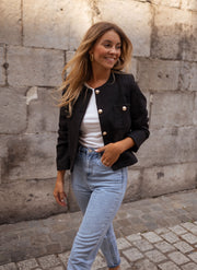 Veste droite à épaulettes portée par une femme, vue de trois-quarts, mains dans les poches