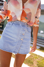 Jupe-short en jean porté par une femme, vue rapprochée, poche, chemisier fleuri