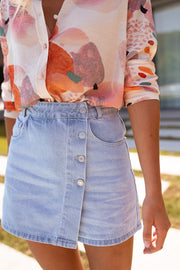 Jupe-short en jean porté par une femme, vue rapprochée, boutons, main dans la poche