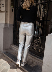 Pantalon effet cuir taille haute porté par une femme, vue de dos, portail noir, baskets blanches