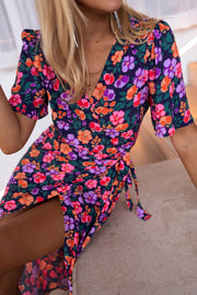 Robe longue cache-cœur fleurie portée par une femme, vue rapprochée, décolleté cache-cœur, manches