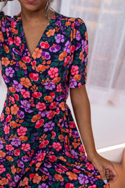 Robe longue cache-cœur fleurie portée par une femme, vue rapprochée, décolleté V, manches bouffantes