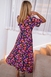 Robe longue cache-cœur fleurie portée par une femme, vue de dos, escalier, cheveux blonds