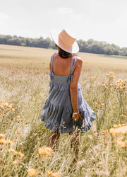 Robe brodée à décolleté carré portée par une femme, vue de dos, champ, chapeau