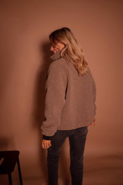 Manteau mouton à col montant porté par une femme, vue de dos, regard sur le côté, jean noir
