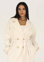 Manteau beige à boutons dorés — détail des revers et des boutons.