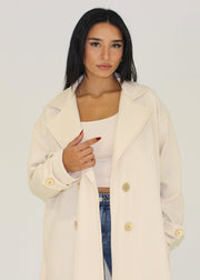 Manteau beige à boutons dorés — détail du boutonnage.