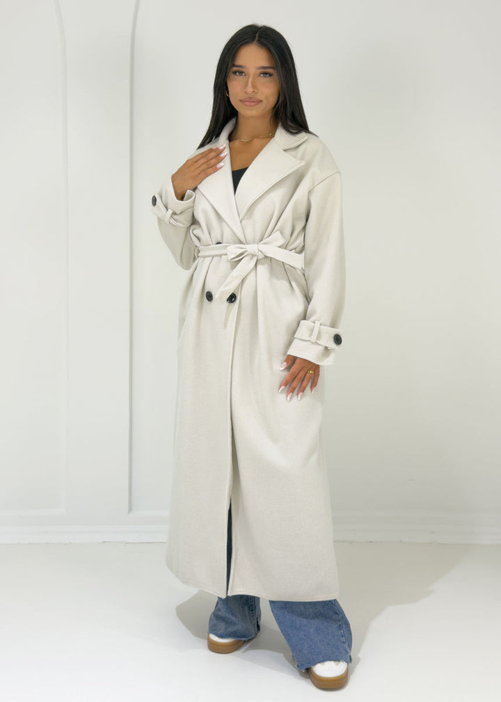Manteau long écru à boutons, vue portée de face, ceinturé