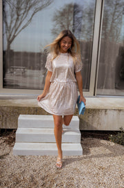 Jupe fluide effet patineuse portée par une femme, vue de trois-quarts, marches, jambe levée