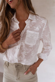 Chemise brodée à manches longues portée par une femme, vue rapprochée, poche poitrine, broderie