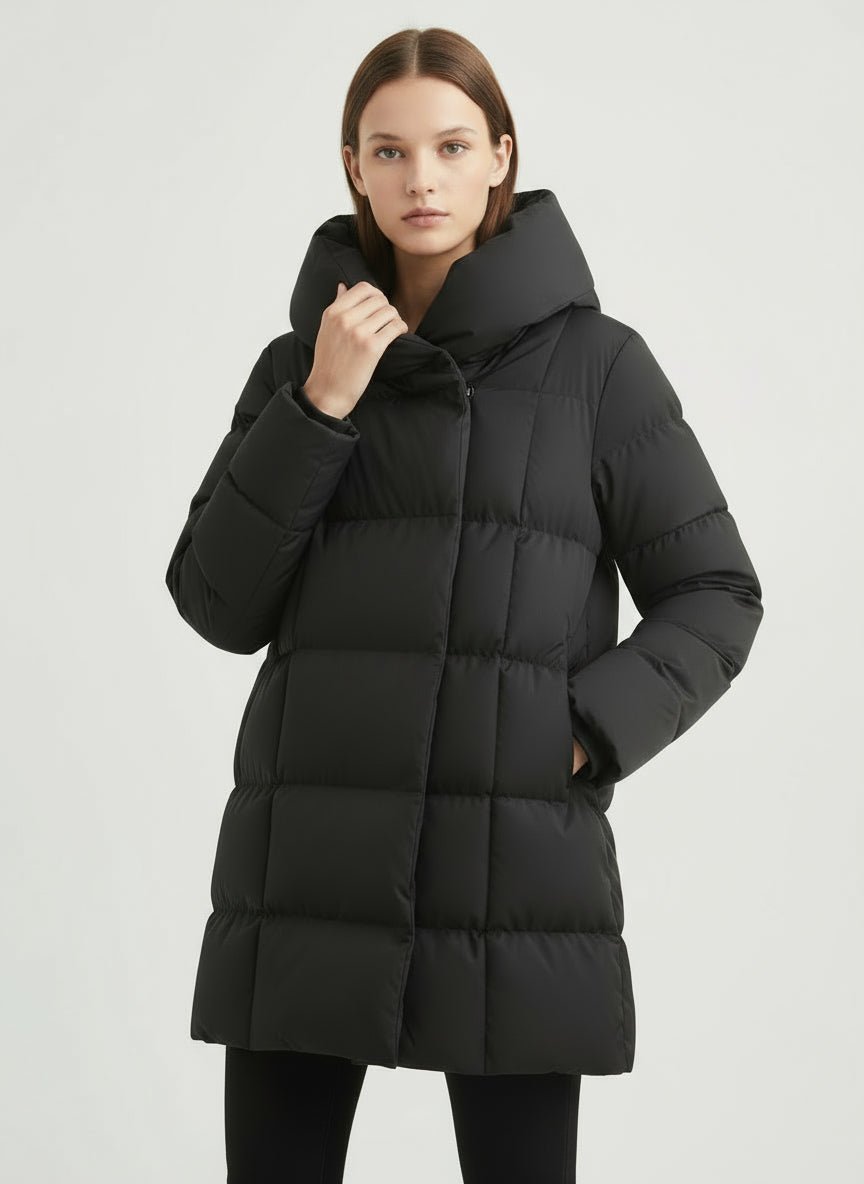 Veste matelassée mi-longue noire — vue portée de face, capuche, regard vers l'objectif