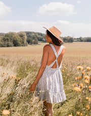 Robe fleurie à volants portée par une femme, vue de dos, champ, chapeau de paille