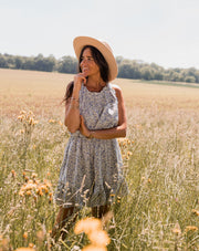 Robe fleurie à volants portée par une femme, vue de face, champ, chapeau