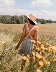 Robe fleurie à volants portée par une femme, vue de dos, champ, fleurs jaunes
