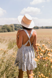 Robe fleurie à volants portée par une femme, vue de dos, chapeau, bretelles croisées