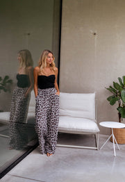 Top bustier élastiqué au dos porté par une femme, silhouette entière, pantalon léopard, canapé