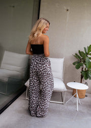 Top bustier élastiqué au dos porté par une femme, vue de dos, pantalon léopard, canapé