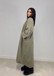 Manteau ouvert à poches plaquées — vue portée de profil, regard par-dessus l'épaule, longueur mi-mollet