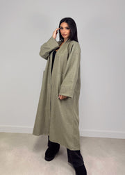 Manteau ouvert à poches plaquées — vue portée de trois-quarts, une main près de la tête, pantalon sombre