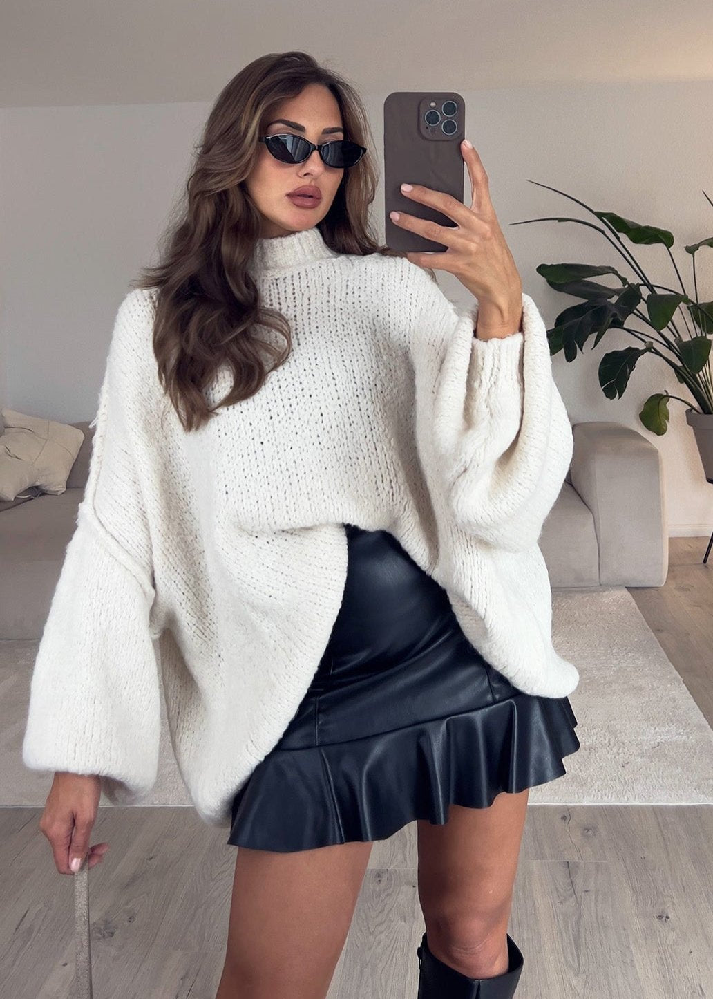 Pull oversize beige clair — selfie au miroir, vue portée de face, jupe courte noire et lunettes de soleil